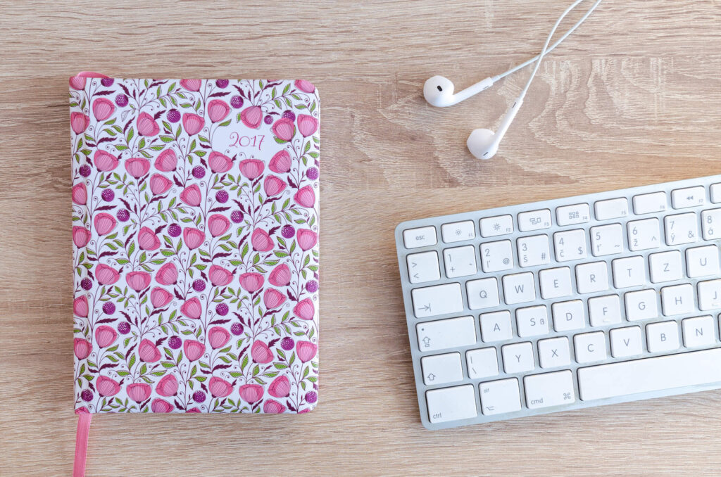 Cute planner with pink and purple flowers and a keyboard for explaining how to stick with using a planner.