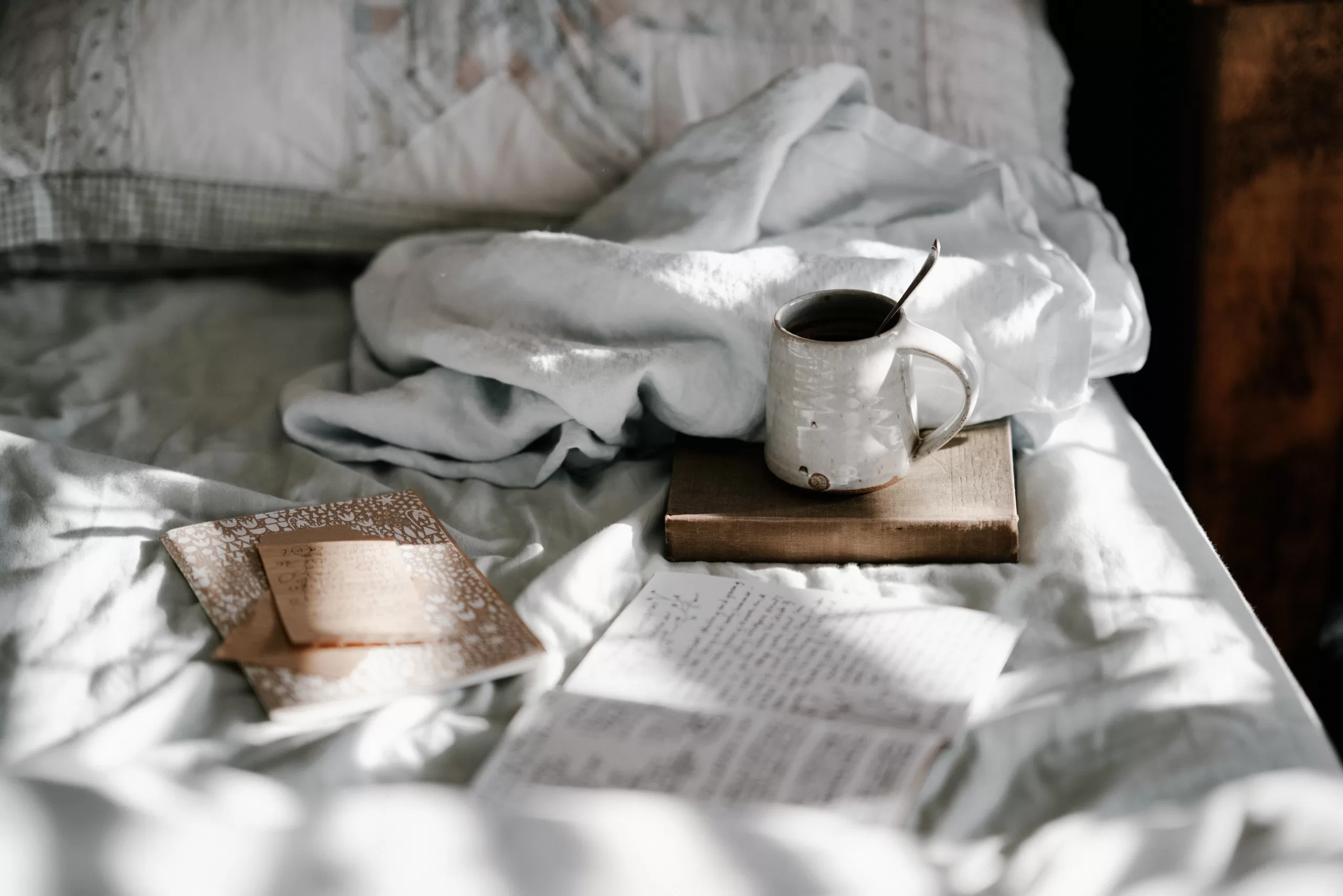 journal on a bed with a cup of coffee to represent a morning journaling routine